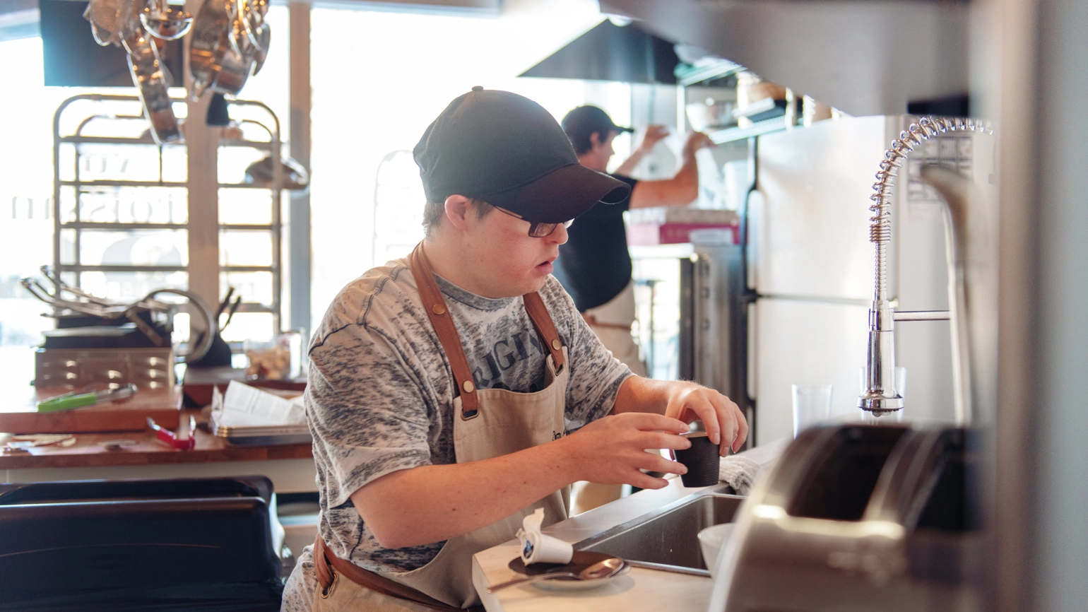 A man cleans dishes inside the kitchen of a small business. A man cleans dishes inside the kitchen of a small business.
