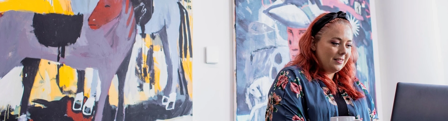 Women working in front of painting on her laptop Women working in front of painting on her laptop