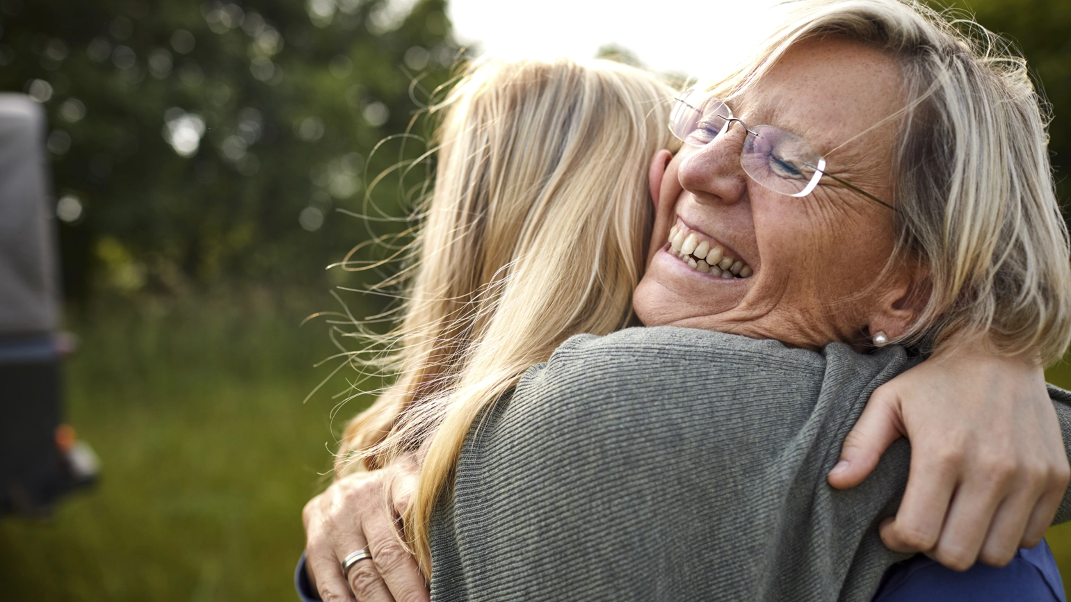Elderly female and young female hugging and smiling Elderly female and young female hugging and smiling