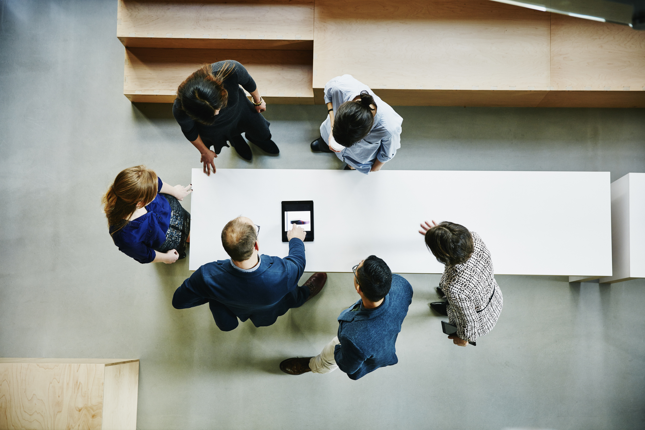 Photograph with birds eye view of office workers around a table working together