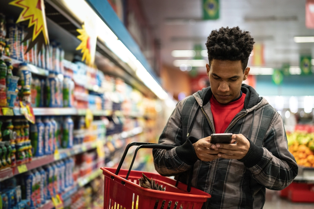 A man looks at his phone as he shops in a supermarket. A man looks at his phone as he shops in a supermarket.