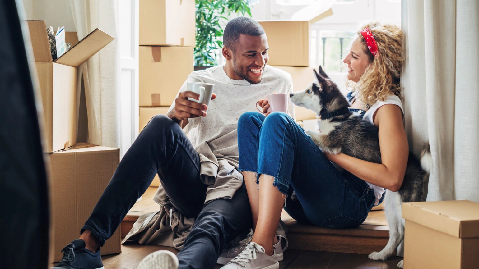 Couple and a dog talking and smiling with unpacked moving boxes Couple and a dog talking and smiling with unpacked moving boxes