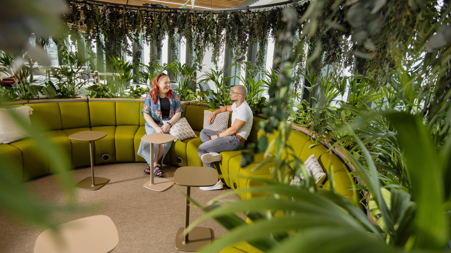 Two employees are talking casually on a curved sofa inside Calon, Legal & General's Welsh HQ Two employees are talking casually on a curved sofa inside Calon, Legal & General's Welsh HQ